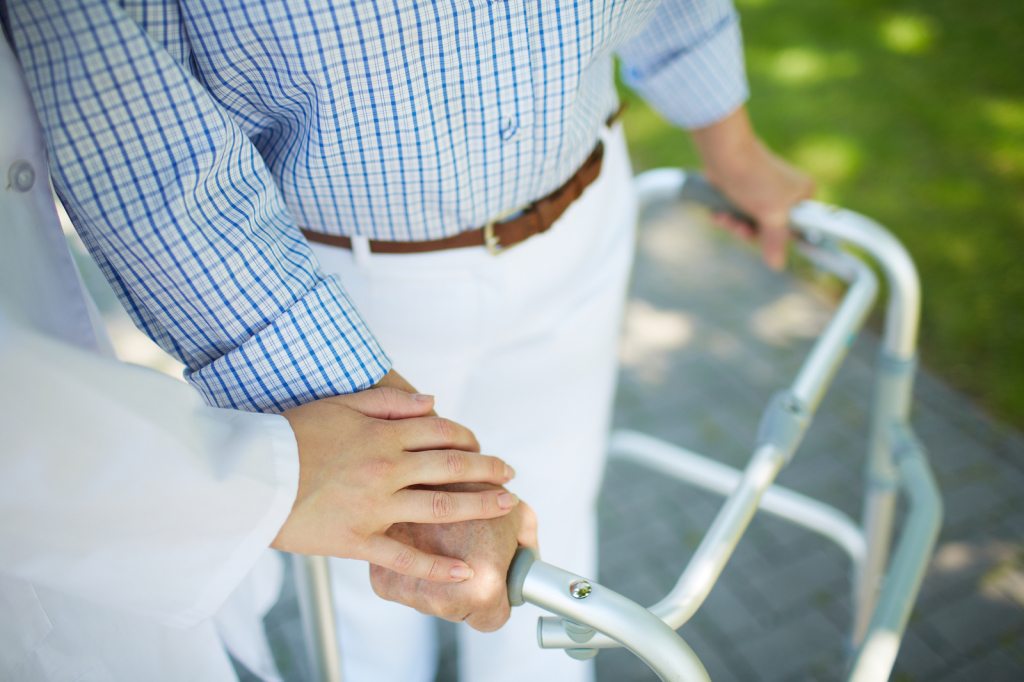 holding elderly person's hand using walker