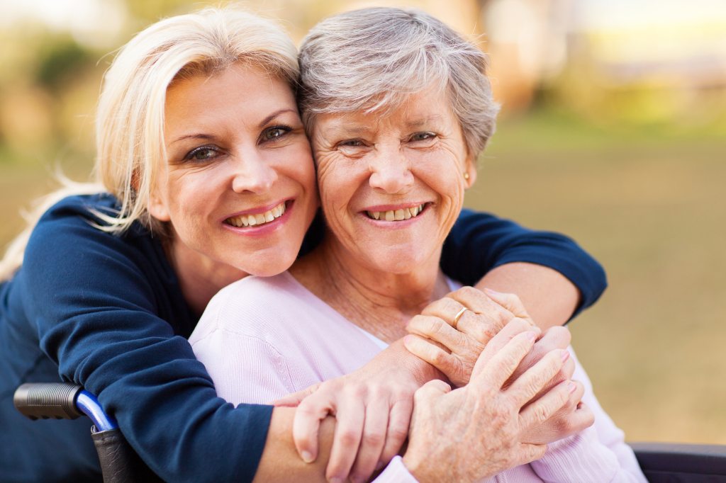 cheerful middle aged woman embracing disabled senior mother outd