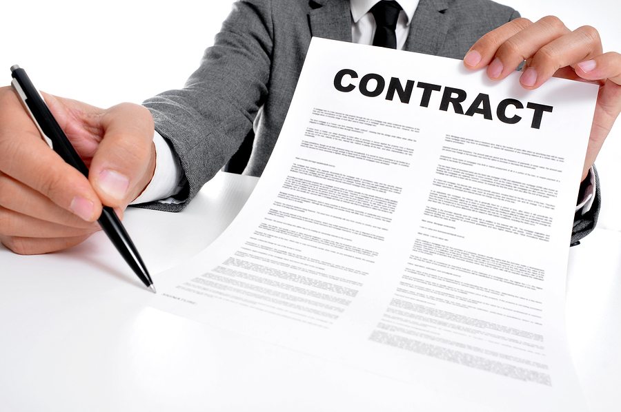 man wearing a suit sitting in a table showing a contract and whe