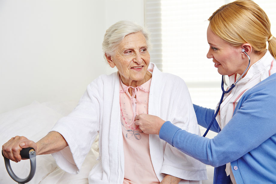 Geriatric nurse ausculting senior citizen woman in nursing home
