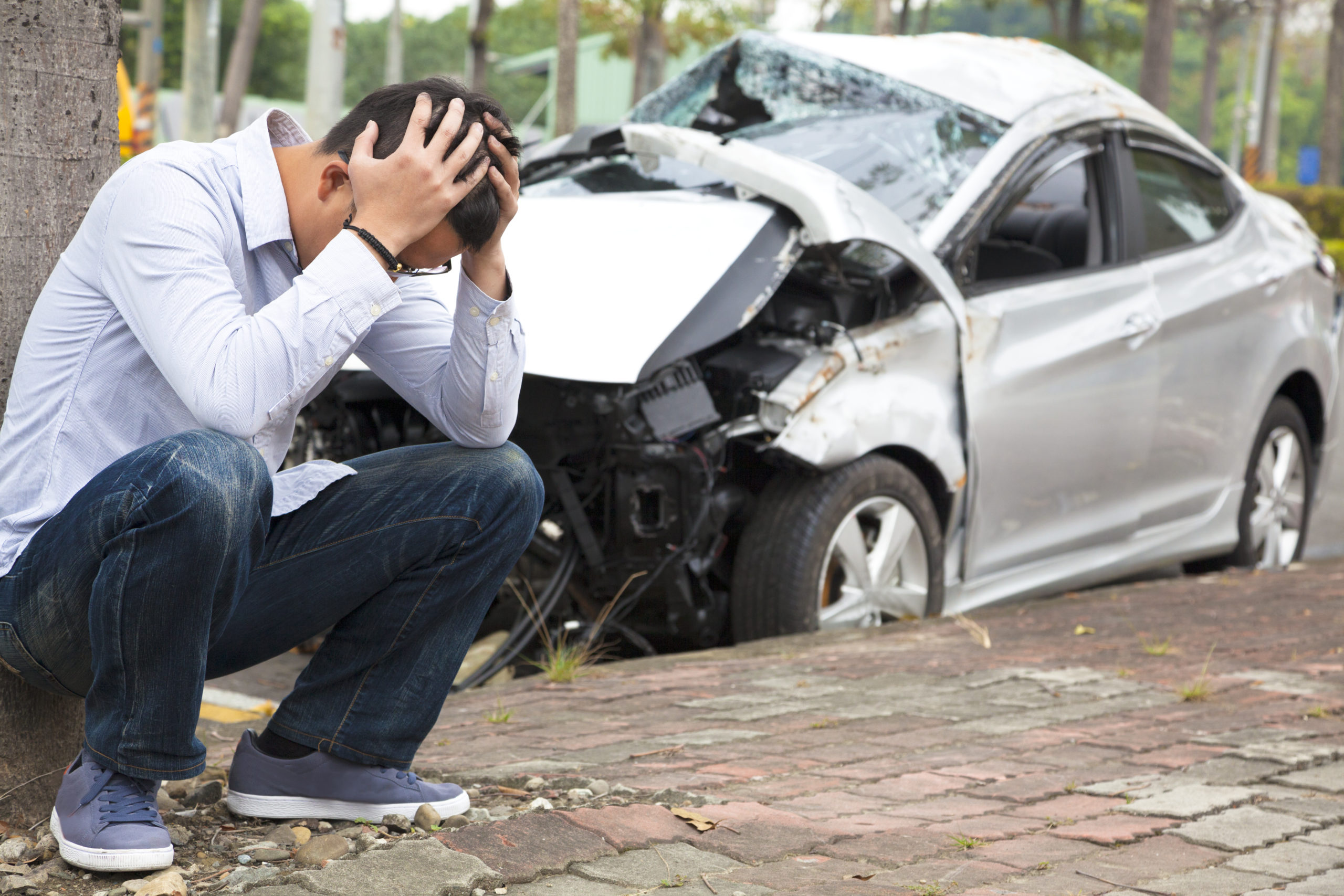Philadelphia Car Accident Lawyer- man sitting beside a wrecked car.