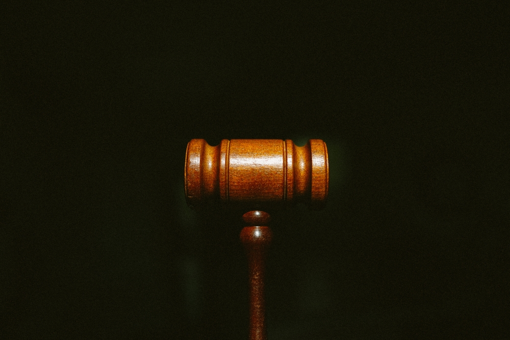 Work Sexual Harassment: Trust Your Feelings - A wooden gavel centered on a dark background with grain.