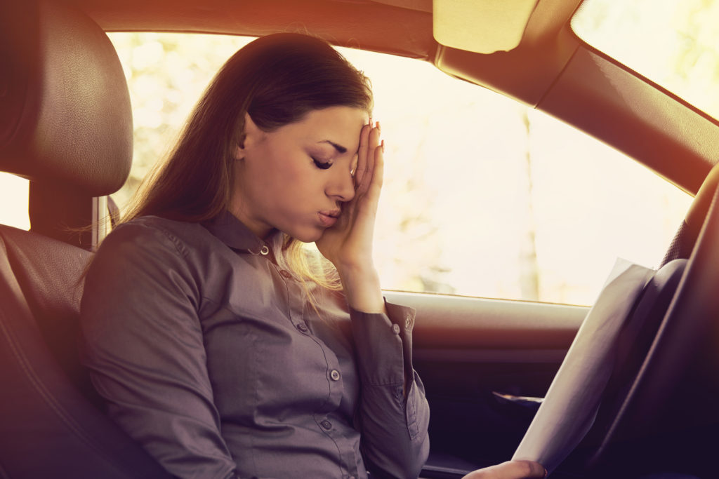 Driver Fatigue & Car Accidents - Stressed woman driver with papers sitting inside her car